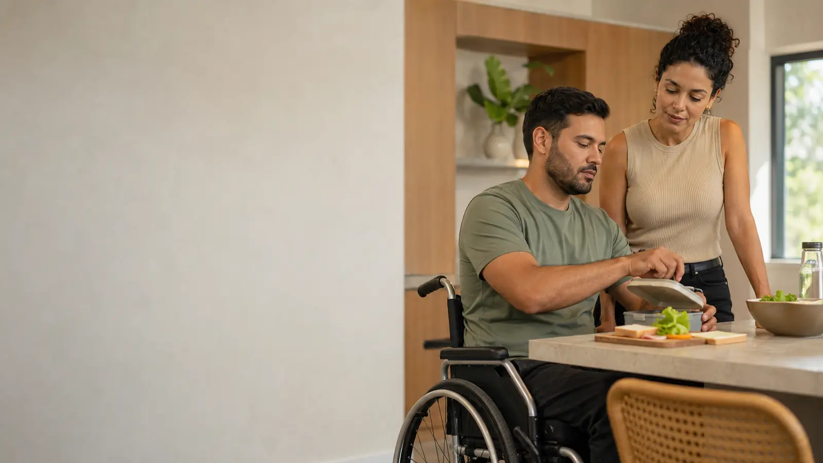 Homem com lesão medular preparando um lanche em cozinha acessível com terapeuta ocupacional